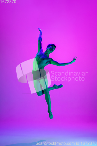 Image of Young and graceful ballet dancer isolated on purple studio background in neon light. Art, motion, action, flexibility, inspiration concept.