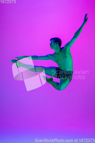 Image of Young and graceful ballet dancer isolated on purple studio background in neon light. Art, motion, action, flexibility, inspiration concept.