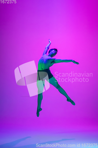 Image of Young and graceful ballet dancer isolated on purple studio background in neon light. Art, motion, action, flexibility, inspiration concept.