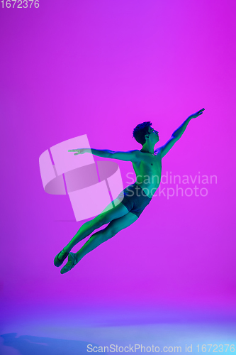 Image of Young and graceful ballet dancer isolated on purple studio background in neon light. Art, motion, action, flexibility, inspiration concept.