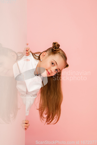 Image of Happy kid, girl isolated on coral pink studio background. Looks happy, cheerful, sincere. Copyspace. Childhood, education, emotions concept