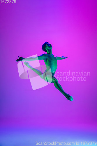 Image of Young and graceful ballet dancer isolated on purple studio background in neon light. Art, motion, action, flexibility, inspiration concept.