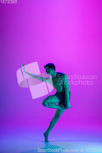 Image of Young and graceful ballet dancer isolated on purple studio background in neon light. Art, motion, action, flexibility, inspiration concept.