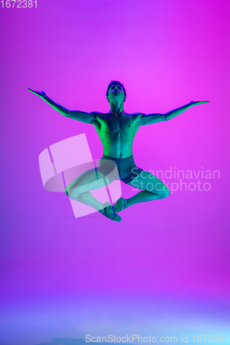 Image of Young and graceful ballet dancer isolated on purple studio background in neon light. Art, motion, action, flexibility, inspiration concept.