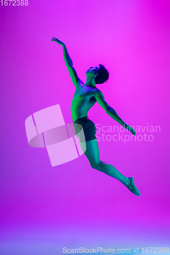 Image of Young and graceful ballet dancer isolated on purple studio background in neon light. Art, motion, action, flexibility, inspiration concept.