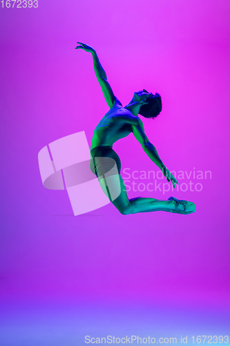 Image of Young and graceful ballet dancer isolated on purple studio background in neon light. Art, motion, action, flexibility, inspiration concept.