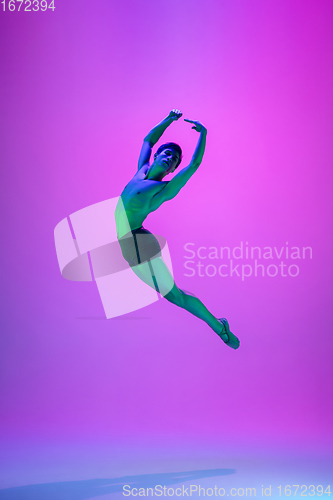 Image of Young and graceful ballet dancer isolated on purple studio background in neon light. Art, motion, action, flexibility, inspiration concept.