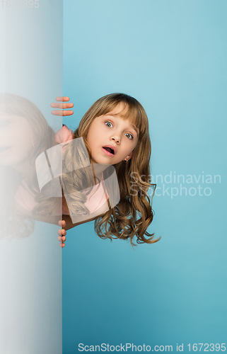 Image of Happy kid, girl isolated on blue studio background. Looks happy, cheerful, sincere. Copyspace. Childhood, education, emotions concept