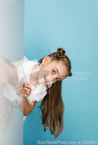 Image of Happy kid, girl isolated on blue studio background. Looks happy, cheerful, sincere. Copyspace. Childhood, education, emotions concept