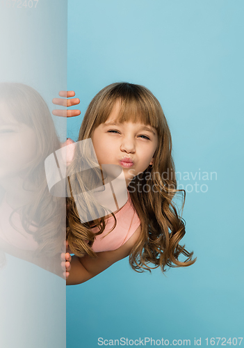 Image of Happy kid, girl isolated on blue studio background. Looks happy, cheerful, sincere. Copyspace. Childhood, education, emotions concept