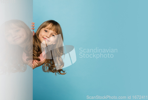 Image of Happy kid, girl isolated on blue studio background. Looks happy, cheerful, sincere. Copyspace. Childhood, education, emotions concept