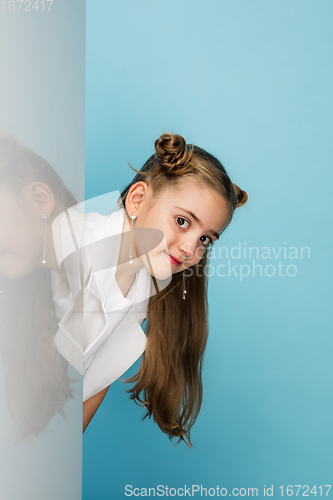 Image of Happy kid, girl isolated on blue studio background. Looks happy, cheerful, sincere. Copyspace. Childhood, education, emotions concept