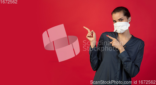 Image of Woman in protective face mask isolated on red studio background. New rules of COVID spreading prevention