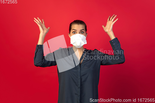 Image of Woman in protective face mask isolated on red studio background. New rules of COVID spreading prevention