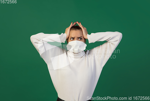 Image of Woman in protective face mask isolated on green studio background. New rules of COVID spreading prevention