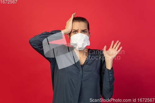 Image of Woman in protective face mask isolated on red studio background. New rules of COVID spreading prevention