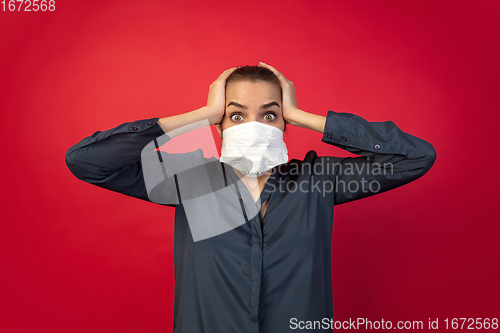 Image of Woman in protective face mask isolated on red studio background. New rules of COVID spreading prevention