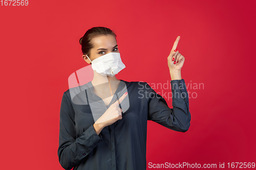 Image of Woman in protective face mask isolated on red studio background. New rules of COVID spreading prevention