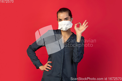 Image of Woman in protective face mask isolated on red studio background. New rules of COVID spreading prevention