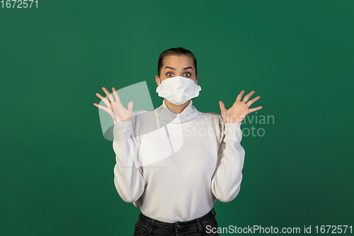 Image of Woman in protective face mask isolated on green studio background. New rules of COVID spreading prevention