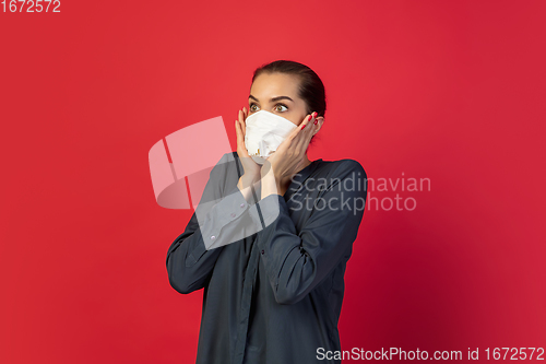 Image of Woman in protective face mask isolated on red studio background. New rules of COVID spreading prevention