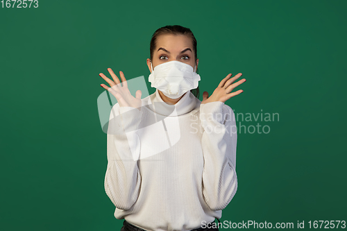 Image of Woman in protective face mask isolated on green studio background. New rules of COVID spreading prevention
