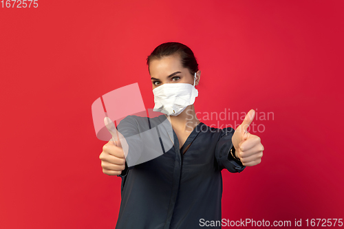 Image of Woman in protective face mask isolated on red studio background. New rules of COVID spreading prevention