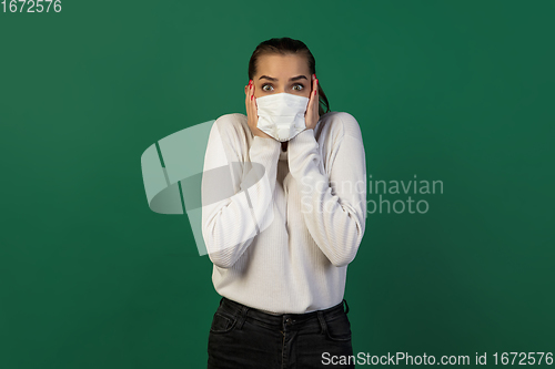 Image of Woman in protective face mask isolated on green studio background. New rules of COVID spreading prevention