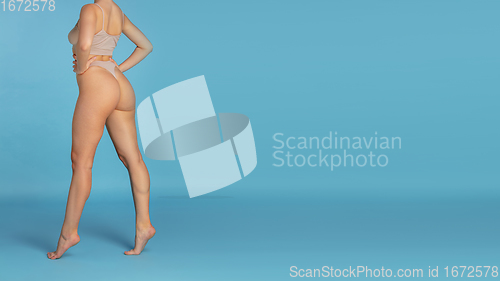 Image of Beautiful body of young caucasian woman isolated on blue studio background