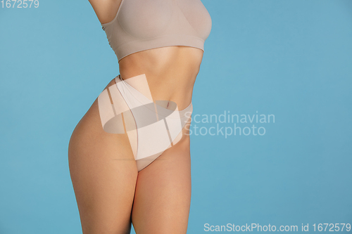 Image of Beautiful body of young caucasian woman isolated on blue studio background