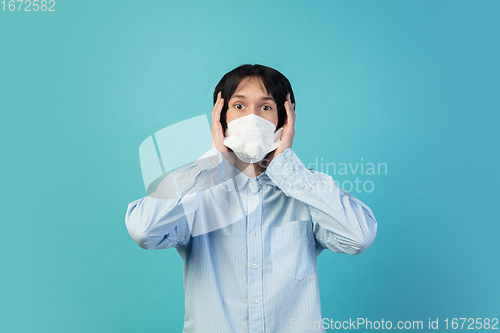 Image of Man in protective face mask isolated on blue studio background. New rules of COVID spreading prevention