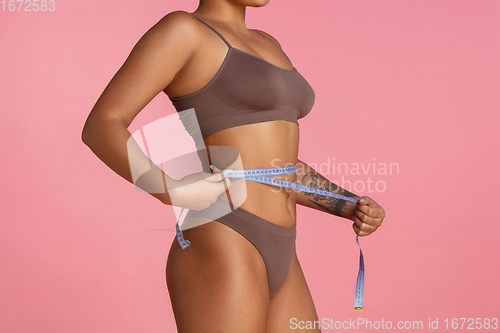 Image of Beautiful body of young african-american woman isolated on pink studio background