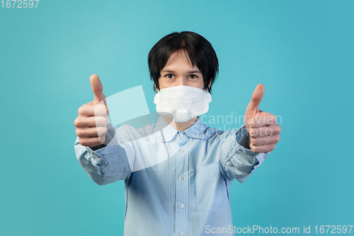 Image of Man in protective face mask isolated on blue studio background. New rules of COVID spreading prevention