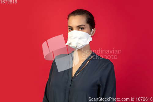 Image of Woman in protective face mask isolated on red studio background. New rules of COVID spreading prevention