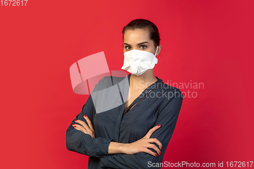 Image of Woman in protective face mask isolated on red studio background. New rules of COVID spreading prevention