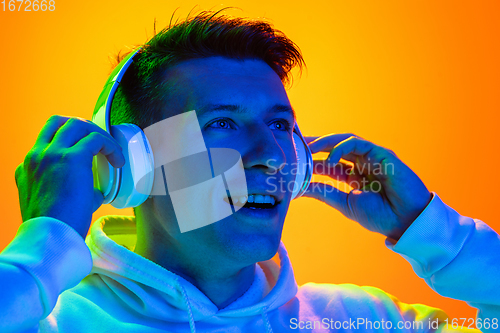 Image of Caucasian beautiful man\'s portrait isolated on yellow studio background in multicolored neon light