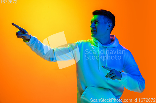 Image of Caucasian beautiful man\'s portrait isolated on yellow studio background in multicolored neon light