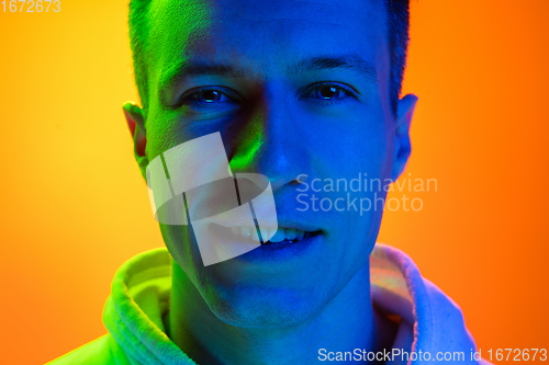 Image of Caucasian beautiful man\'s portrait isolated on yellow studio background in multicolored neon light