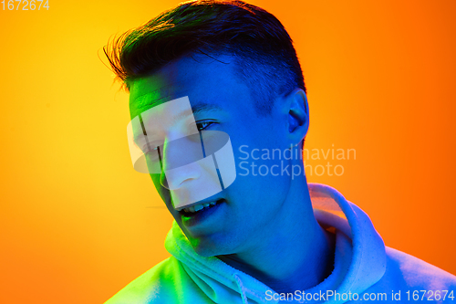 Image of Caucasian beautiful man\'s portrait isolated on yellow studio background in multicolored neon light