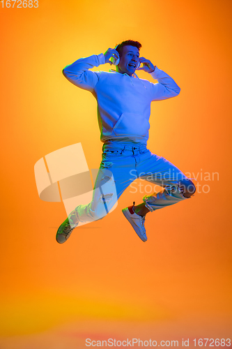 Image of Caucasian beautiful man\'s portrait isolated on yellow studio background in multicolored neon light