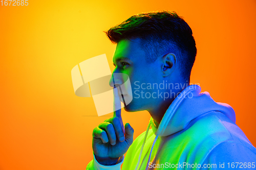 Image of Caucasian beautiful man\'s portrait isolated on yellow studio background in multicolored neon light