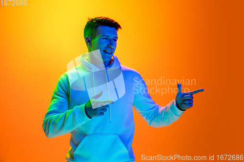 Image of Caucasian beautiful man\'s portrait isolated on yellow studio background in multicolored neon light