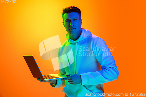 Image of Caucasian beautiful man\'s portrait isolated on yellow studio background in multicolored neon light