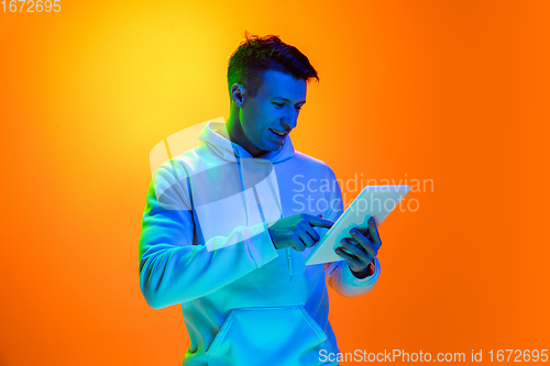 Image of Caucasian beautiful man\'s portrait isolated on yellow studio background in multicolored neon light