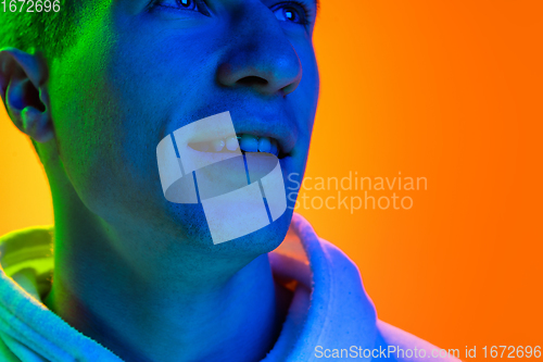 Image of Caucasian beautiful man\'s portrait isolated on yellow studio background in multicolored neon light