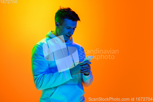 Image of Caucasian beautiful man\'s portrait isolated on yellow studio background in multicolored neon light