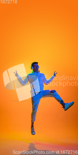 Image of Caucasian beautiful man\'s portrait isolated on yellow studio background in multicolored neon light