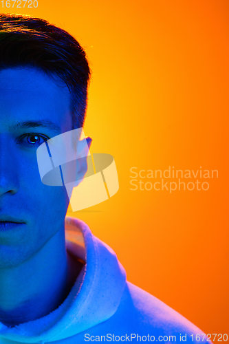 Image of Caucasian beautiful man\'s portrait isolated on yellow studio background in multicolored neon light