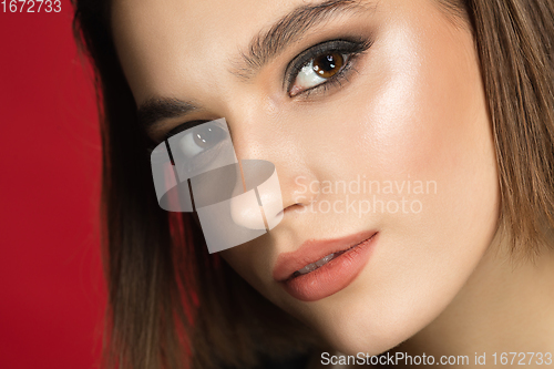Image of Portrait of female fashion model isolated on red studio background. Style and beauty concept. Close up.