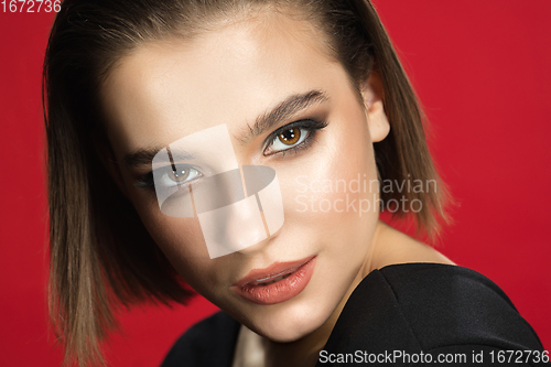 Image of Portrait of female fashion model isolated on red studio background. Style and beauty concept. Close up.